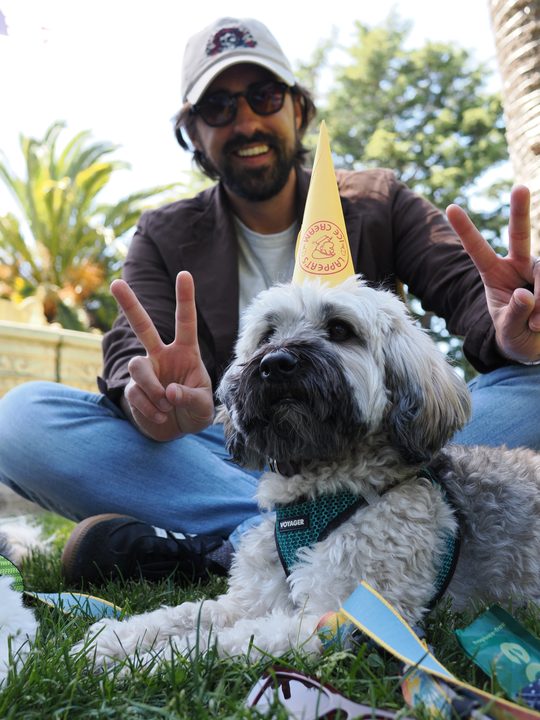 Neil Holt making peace signs behind Ziggy, who is wearing a paper party hat